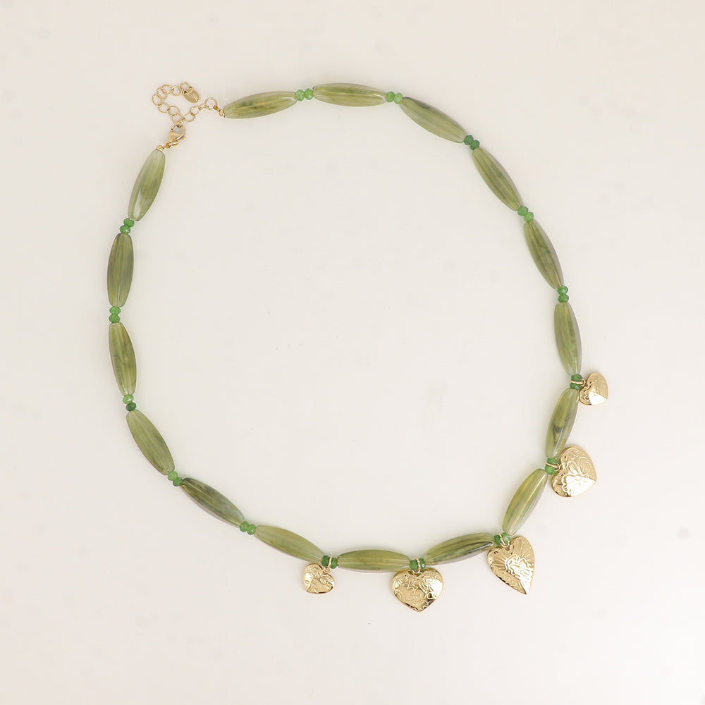 Necklace with green beads and gold heart-shaped charms on a light background. Solelle. Bohm Paris. Yerevan, Armenia