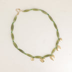 Necklace with green beads and gold heart-shaped charms on a light background. Solelle. Bohm Paris. Yerevan, Armenia