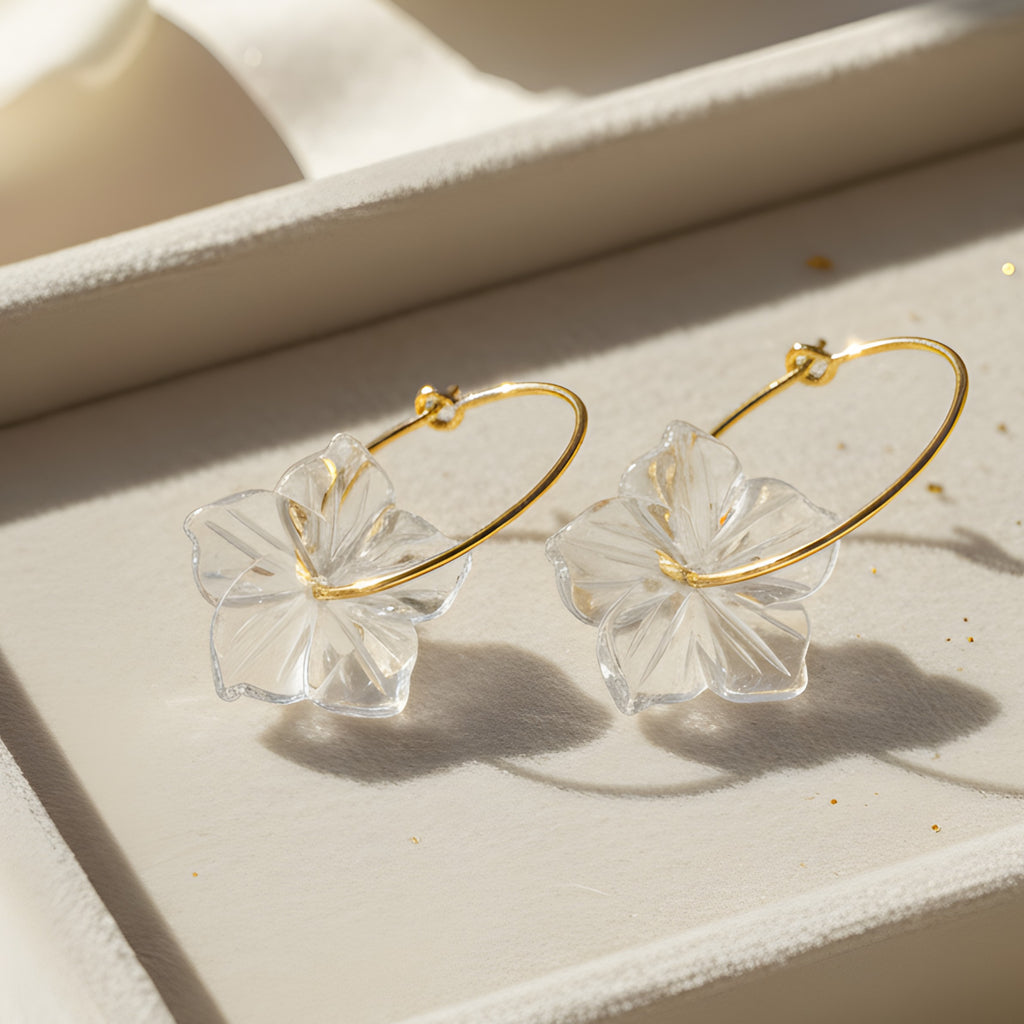 Gold hoop earrings with clear leaf-like connectors on a light background