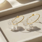 Gold hoop earrings with clear leaf-like connectors on a light background
